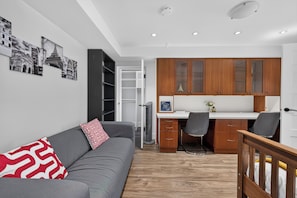 A modern apartment with a grey sofa, wooden cabinets, and a white desk. - Tranquil Garden Level Retreat near UBC & Airport (Vancouver)