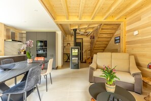 Een modern interieur met een eetgedeelte, keuken en woonruimte, met zichtbare houten balken en een trap.