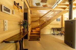 Een houten interieur met een trap, een kachel en een plant.