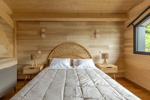 Ein Schlafzimmer mit Holzwänden, einem Bett, zwei Nachttischen und einem Fenster.