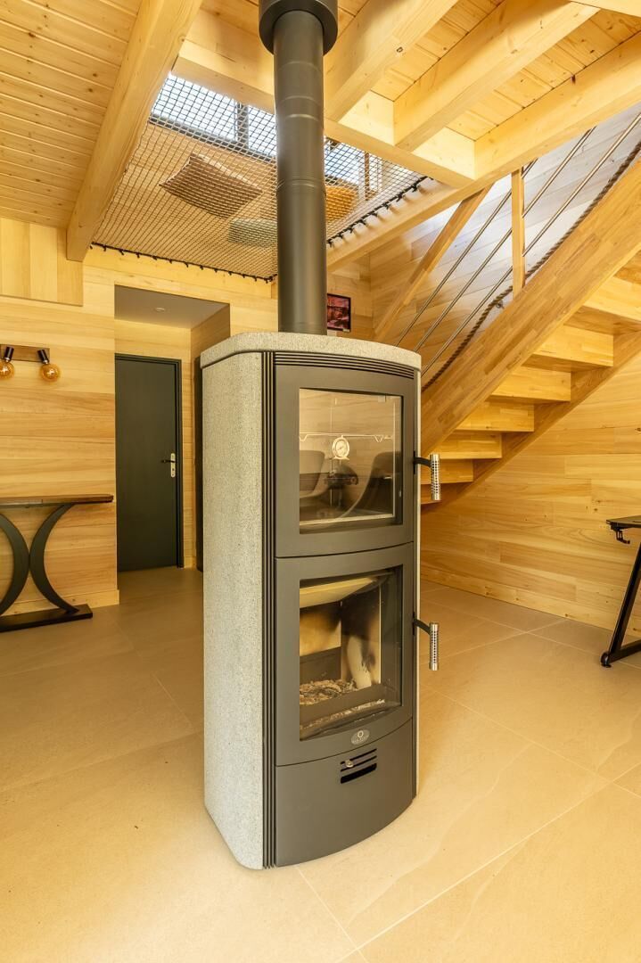 A wood-burning stove in a room with wooden beams and a sloped ceiling.