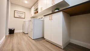 A laundry room with white cabinets, a washing machine, and a dryer.