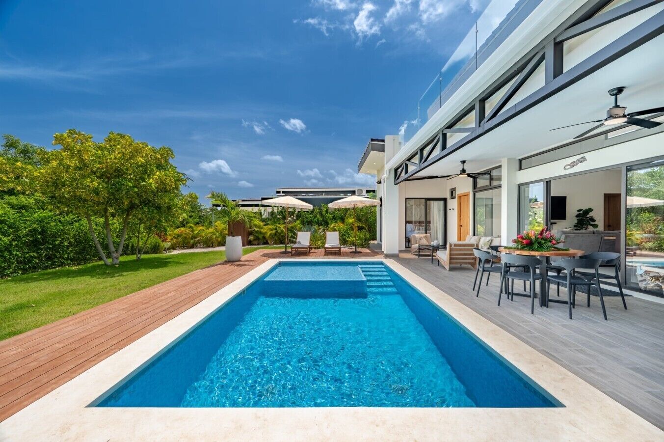 Ein modernes Haus mit Swimmingpool, Gartenmöbeln und einer Terrassenanlage.