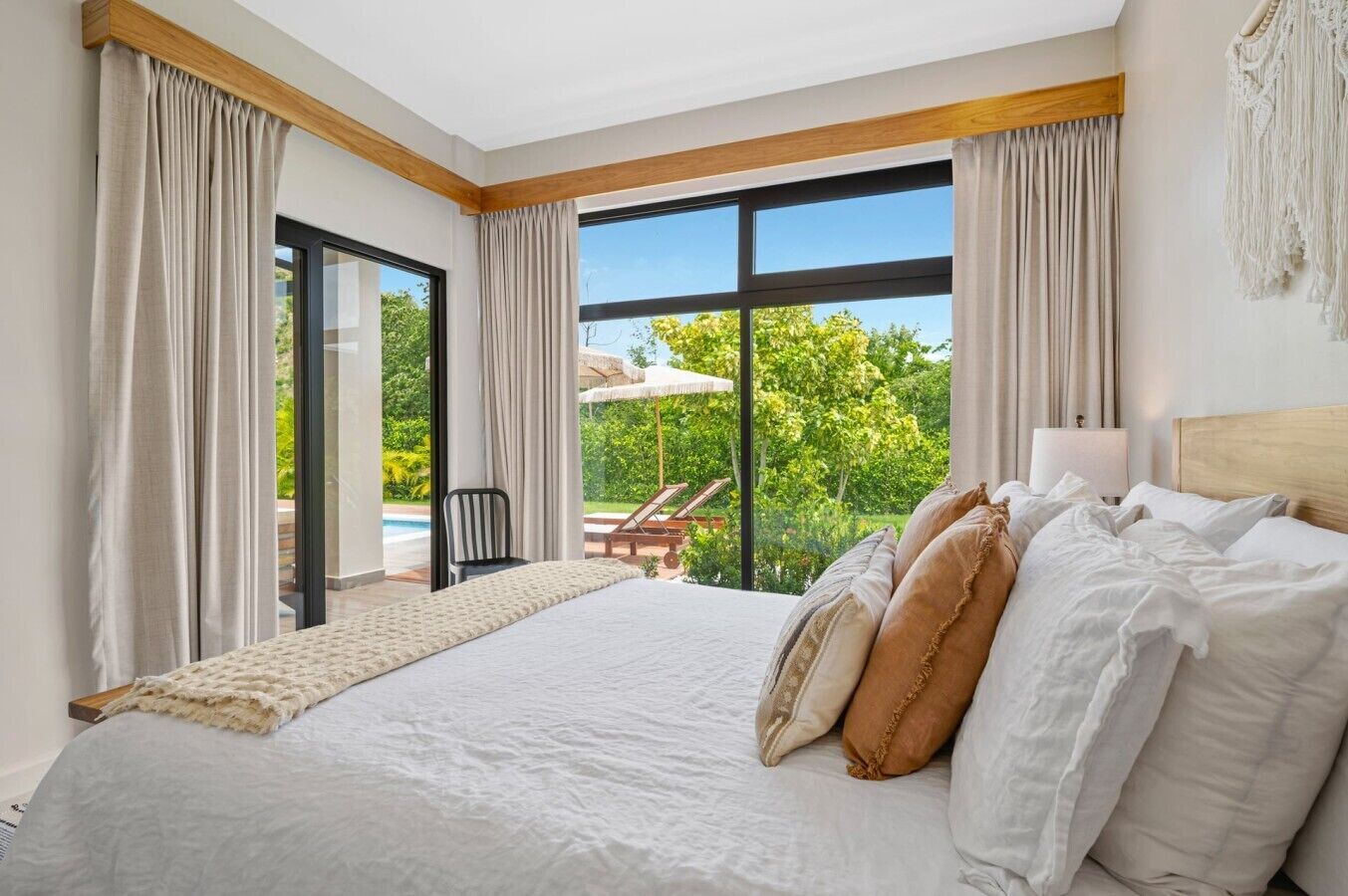 Une chambre avec un grand lit, une vue sur une piscine et un espace verdoyant, ainsi qu’une porte-fenêtre coulissante.