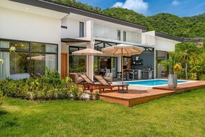 Een modern huis met een zwembad, buiten zitplaatsen en een keukenhoek.