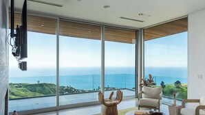 A modern interior with large windows offering a view of the ocean and hills. - Casa Azure Estate by Oraklus (Malibu)