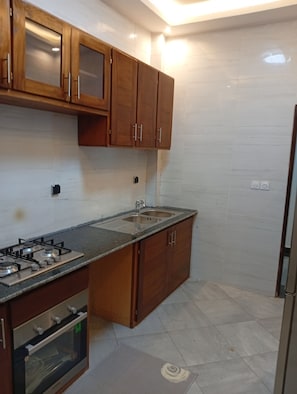 Una cocina con gabinetes de madera, una estufa a gas, un lavamanos y un refrigerador.