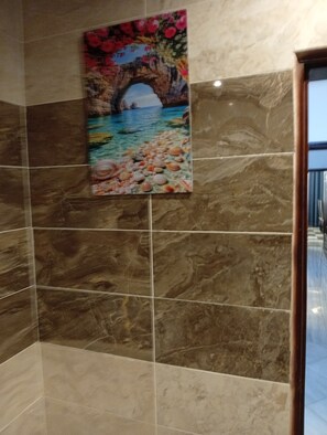 A tiled wall with a painting of a coastal scene. - Résidence Prestige KGV Appt 304 (Douala)