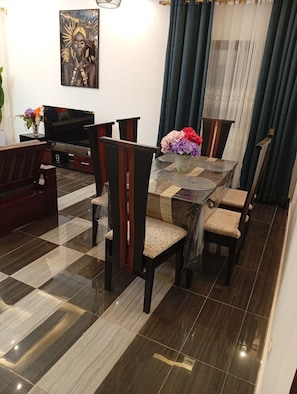 Un comedor con piso a cuadros, una mesa con un jarrón de flores y un cuadro en la pared.