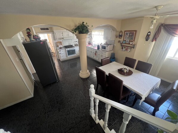 A dining area with a table and chairs, a kitchen in the background, and a staircase leading to another level.