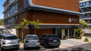 A modern building with a sign for 'SETAI AQUAMARIS.' There are three cars parked in front. - Nawi Beachfront Escape Apartment - Pool, Gym & Ocean Access (João Pessoa)