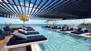 A poolside area with lounge chairs and umbrellas, overlooking a clear blue sky and water. - Nawi Beachfront Escape Apartment - Pool, Gym & Ocean Access (João Pessoa)