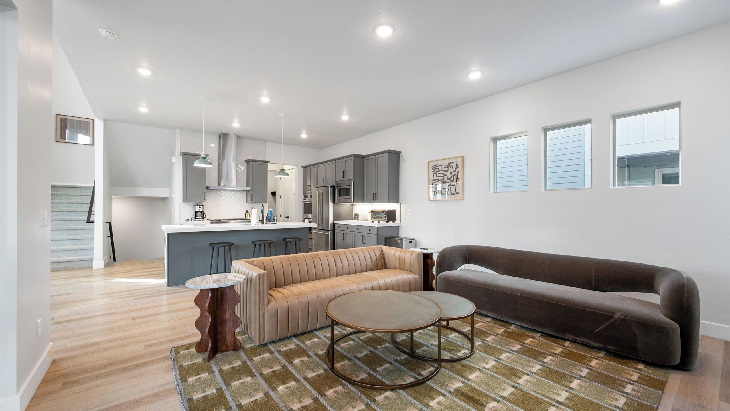 A modern living room with a sofa, a round coffee table, and a patterned rug.