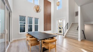 A spacious room with a large dining table, wooden chairs, a staircase, and a view of the outdoors. - Poppy & Pine by Avantstay Sleeps 14 + Hot Tub Game Room + Fire Pit Silver Creek + Canyons (Park City)