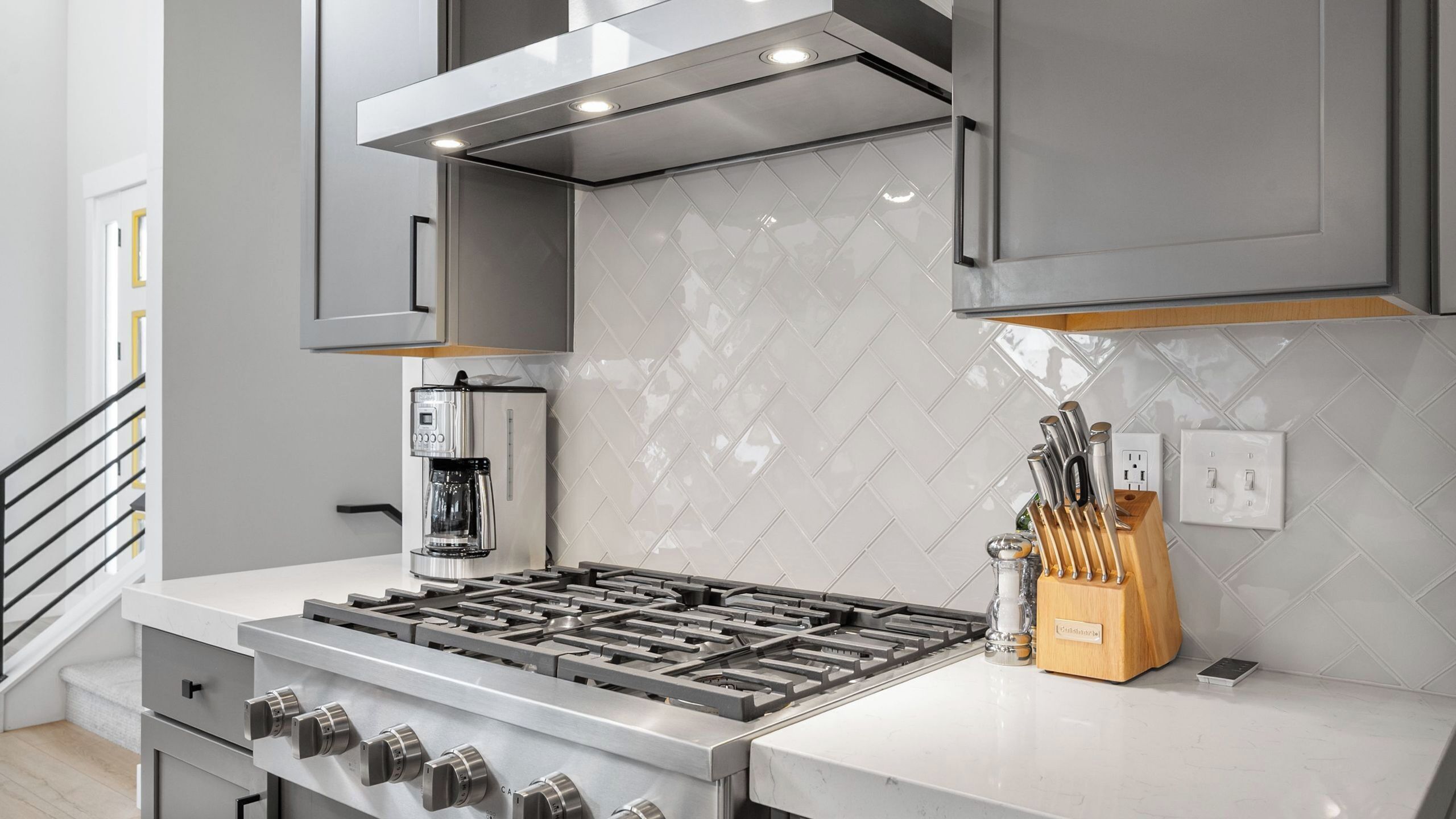 Une cuisine moderne équipée d’une cuisinière à gaz, d’une machine à café et d’un bloc à couteaux.