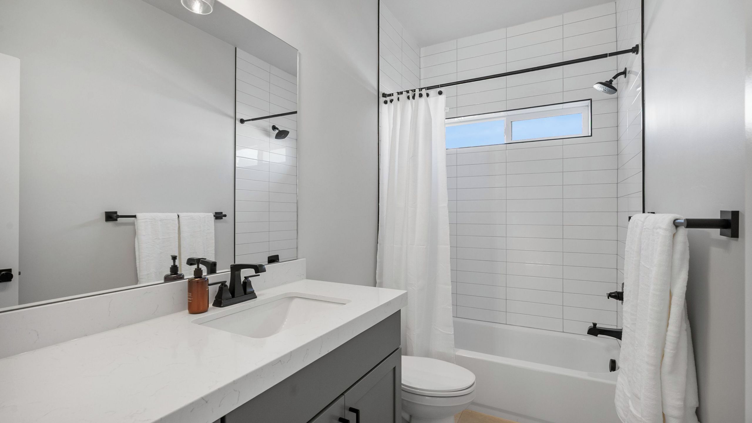 A modern bathroom with a white sink, mirror, and bathtub.