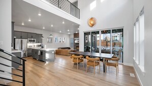 A modern kitchen with stainless steel appliances, a dining area with a wooden table and chairs, and a large window overlooking a snowy landscape. - Poppy & Pine by Avantstay Sleeps 14 + Hot Tub Game Room + Fire Pit Silver Creek + Canyons (Park City)