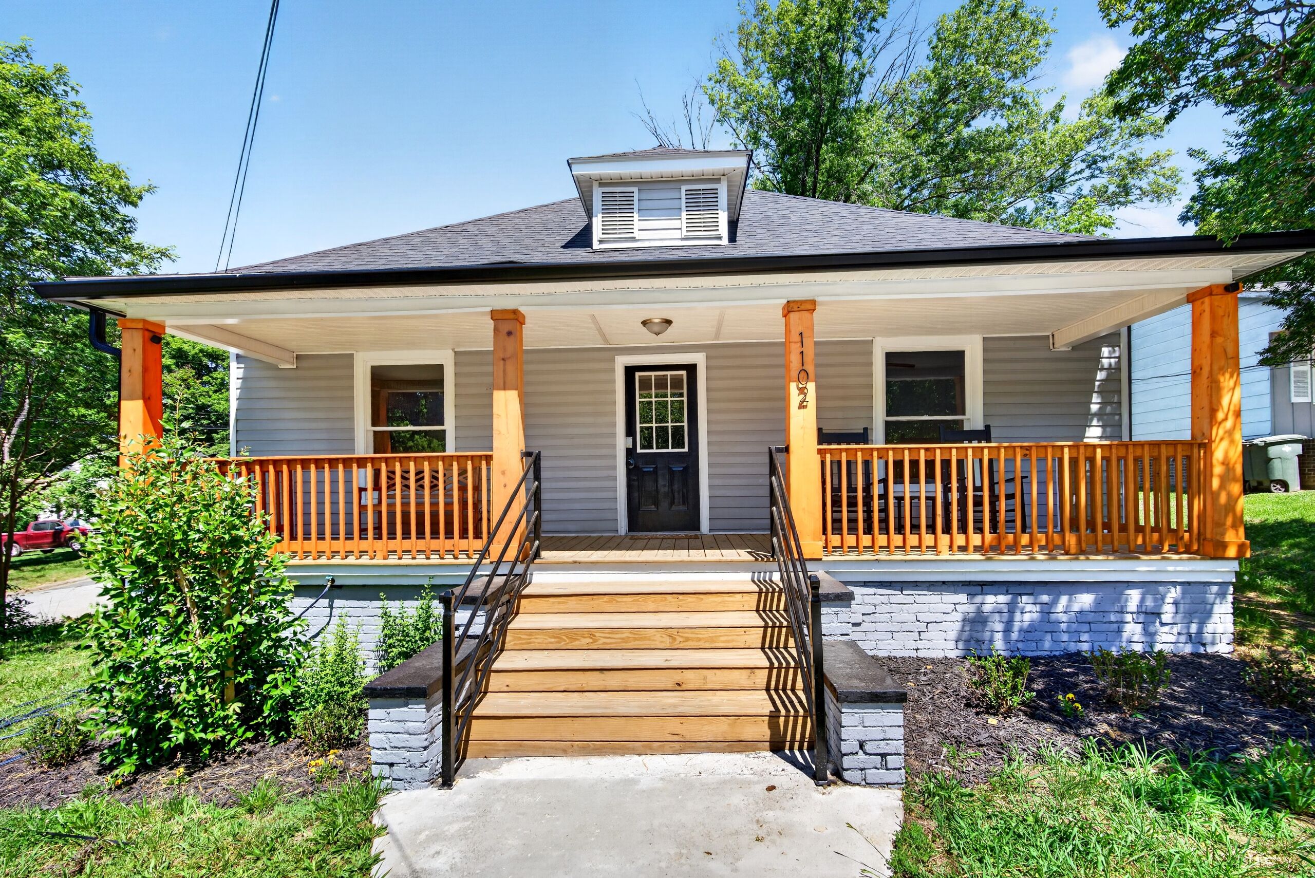 A two-story house with a porch, a front door, and a small window.