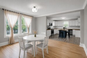 A modern kitchen with white cabinets, a central island, and a dining area with a round table and chairs. - Newly Renovated Furnished Home | Ideal for Corporate & Insurance Housing (Salisbury)