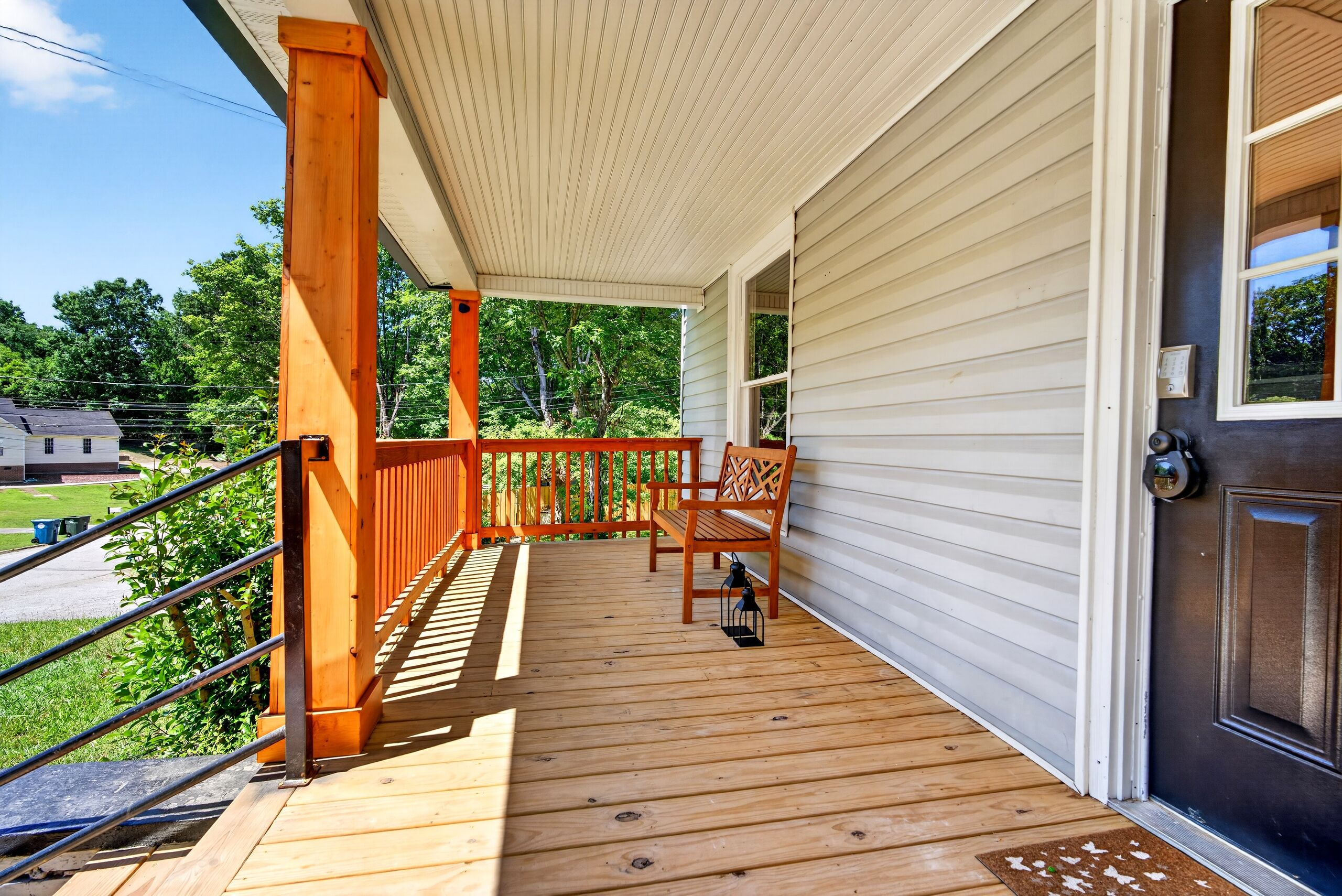 A wooden porch with a bench, a door, and a railing.