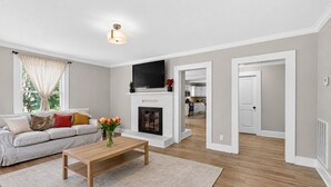 Ein Wohnzimmer mit einer Couch, einem Couchtisch, einem Kamin und einem an der Wand montierten Fernseher.
