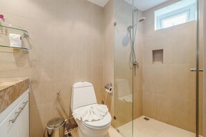 A bathroom with a toilet, shower, and glass-enclosed shower stall. - Panoramic 1BR Pool, Sauna kata ocean view C196 (Karon)