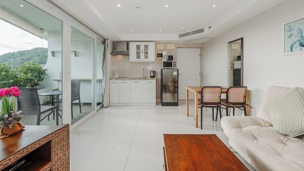 Una cocina moderna con armarios blancos, un refrigerador de acero inoxidable y un comedor con mesa y sillas.