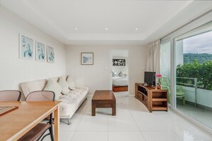 Una sala de estar moderna con sofá, mesa de centro, mueble para TV y un balcón con vistas.