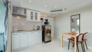 Una cocina moderna con armarios blancos, un refrigerador negro, un microondas y una mesa de comedor con sillas.