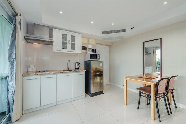 Una cocina moderna con armarios blancos, un refrigerador negro, un microondas y una mesa de comedor con sillas.