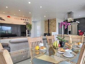 A modern dining area with a glass table, wooden chairs, and a variety of breakfast items. - L'écrin - PLOURHAN - Gîte (PLOURHAN)