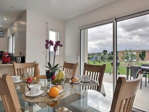 A dining area with a glass table, chairs, and a view of the outdoors. - L'écrin - PLOURHAN - Gîte (PLOURHAN)
