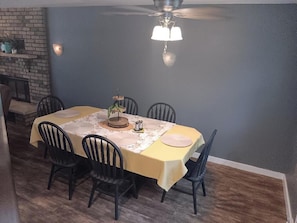 A dining area with a table set for six, chairs, a ceiling fan, and a brick wall. - Spacious 3-bedroom/2.5 bath house in gorgeous Dubuque with AC (Dubuque)