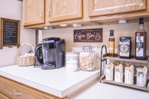 Eine Küchenarbeitsplatte mit einer Kaffeemaschine, einem Schild für den Coffee Bar und verschiedenen Gläsern mit Zutaten.