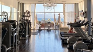 A gym with exercise equipment, a large chandelier, and a view of the sea. - Icon Vallarta · Style, Comfort and Pool (Puerto Vallarta)