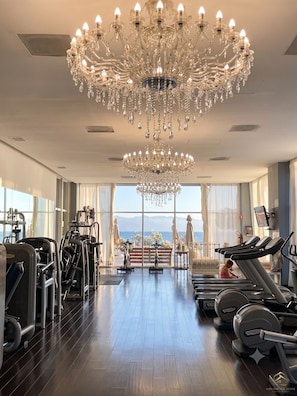 A gym with exercise equipment, a large chandelier, and a view of the sea. - Icon Vallarta · Style, Comfort and Pool (Puerto Vallarta)