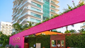 A modern hotel entrance with a prominent pink archway, a sign reading 'ICON VALLARTA,' and a lush green hedge. - Icon Vallarta · Style, Comfort and Pool (Puerto Vallarta)