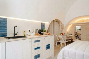Une chambre d’hôtel compacte comprenant un coin cuisine, un espace repas et un lit.
