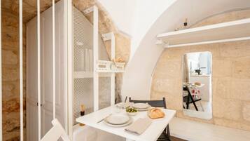A dining area with a table set for two, a mirror, and a stone wall.