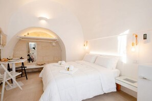 Una habitación de hotel moderna con una cama, un escritorio, un espejo y una pequeña mesa.