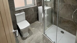 A modern bathroom with a glass shower enclosure, a toilet, and a sink. - Fabulous 3-bedroom house in charming Bircotes for your getaway (Bircotes)
