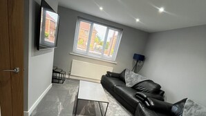 A living room with a sofa, a coffee table, and a TV mounted on the wall. - Fabulous 3-bedroom house in charming Bircotes for your getaway (Bircotes)