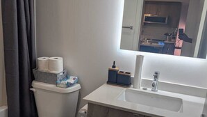 Um banheiro moderno com vaso sanitário, pia, espelho e lixeira.