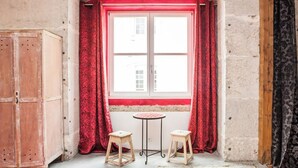 A room with a window, a wooden cabinet, and two stools. - Grand Historic Alfama Apartment, 4BR, 2WC (Lisboa)