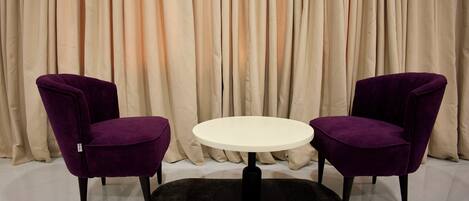 Una habitación con dos sillas moradas, una mesa redonda y un tapete negro.