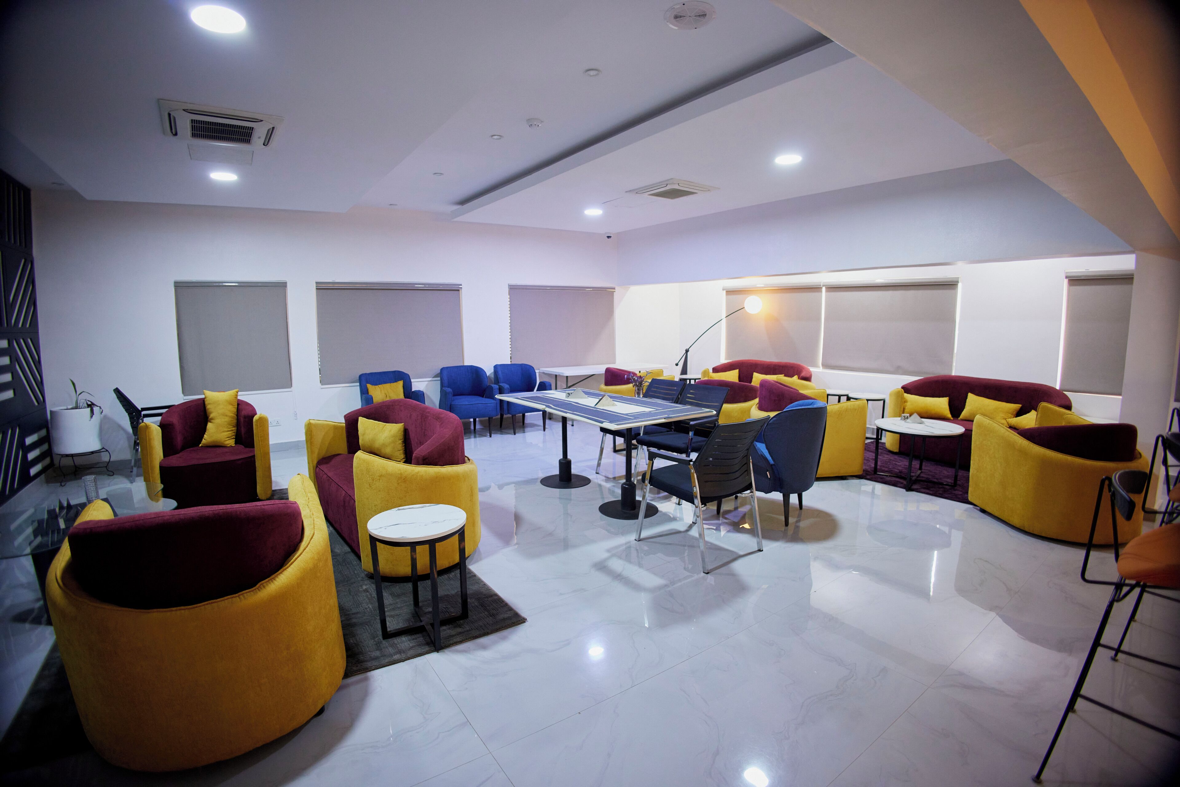 A modern lounge area with multiple seating options, including sofas and chairs, a ping pong table, and a flat-screen TV.