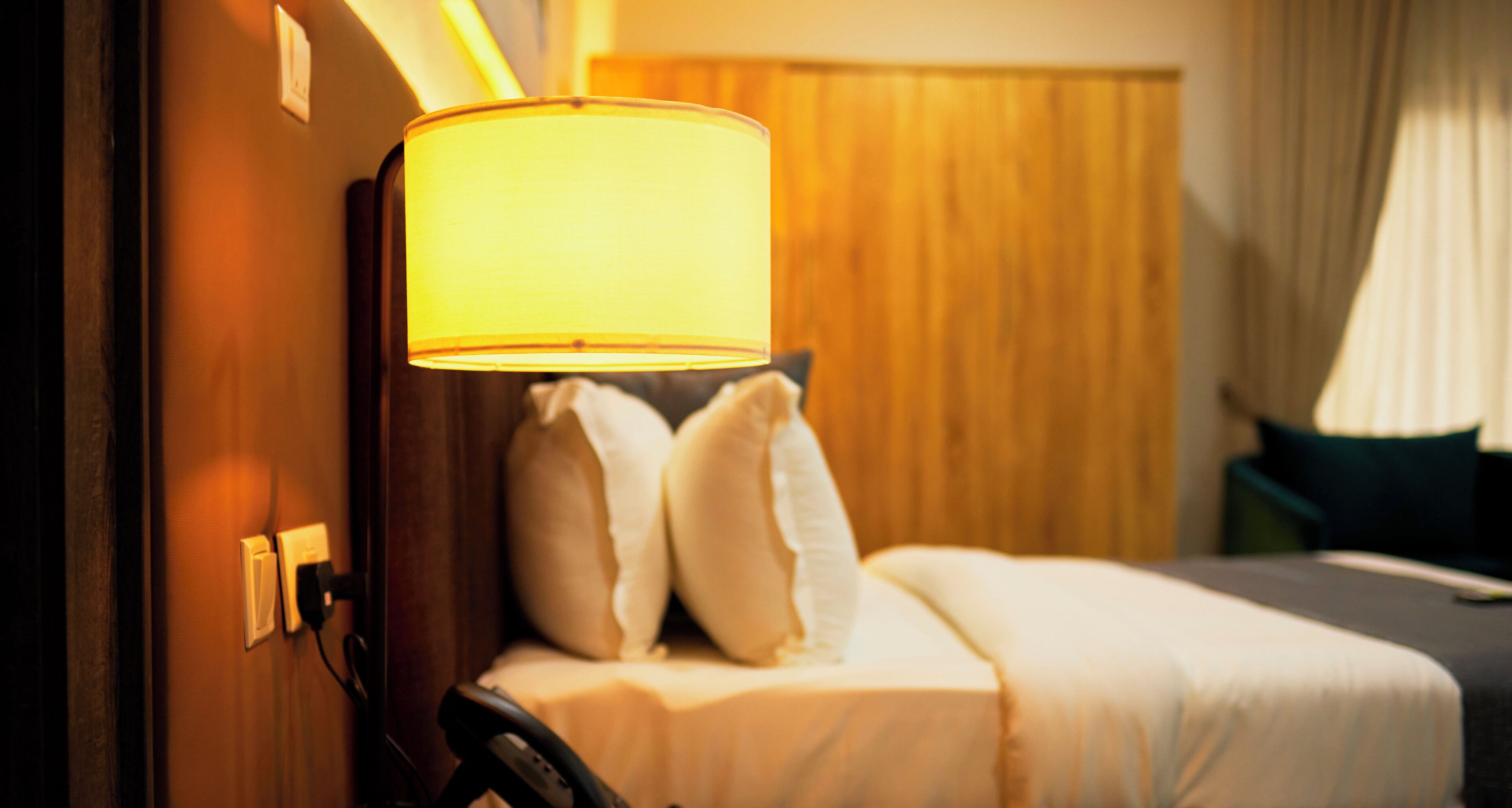 Una habitación de hotel con cama, almohadas, lámpara y teléfono.
