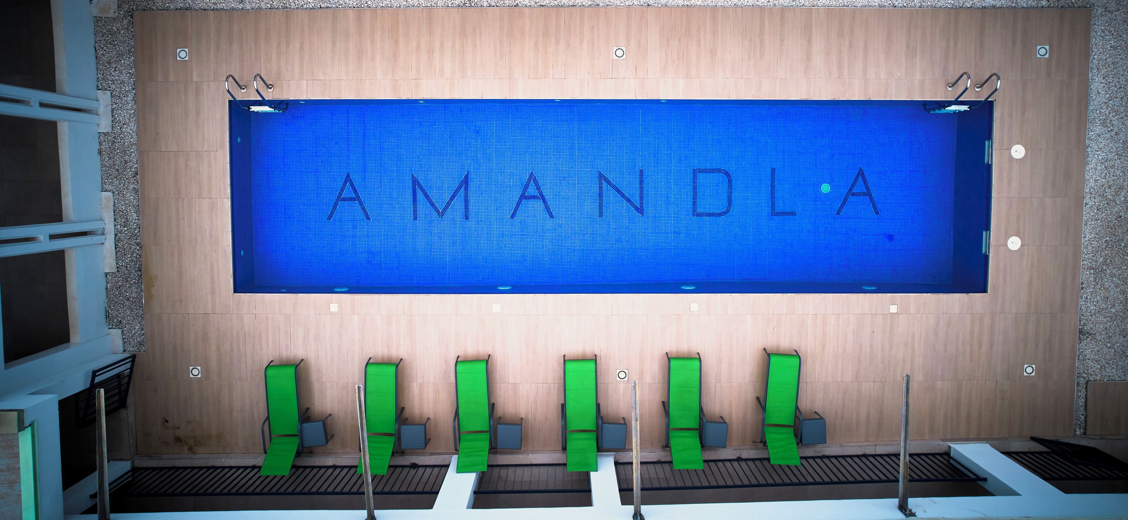 Ein Badezimmer mit einer Holzwand, einem blauen Schild mit der Aufschrift 'AMANDA' und grünen Stühlen.