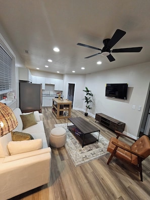 A modern living room with a sofa, coffee table, ottoman, and a ceiling fan. - Charming 1-bedroom apartment with AC in Fort Mill (Fort Mill)