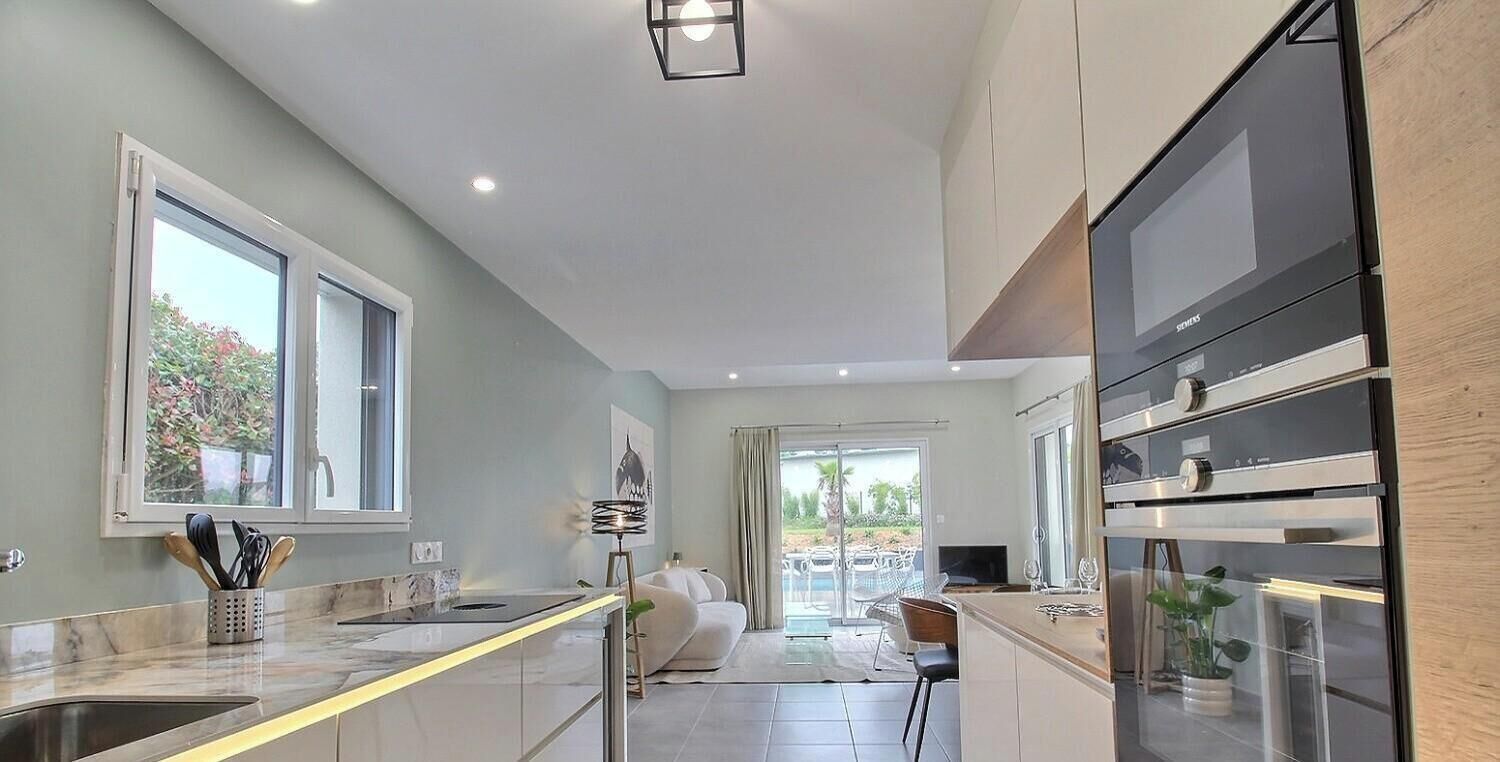 Una cucina moderna con un'isola grande, forno integrato e una porta scorrevole in vetro che dà su un patio.